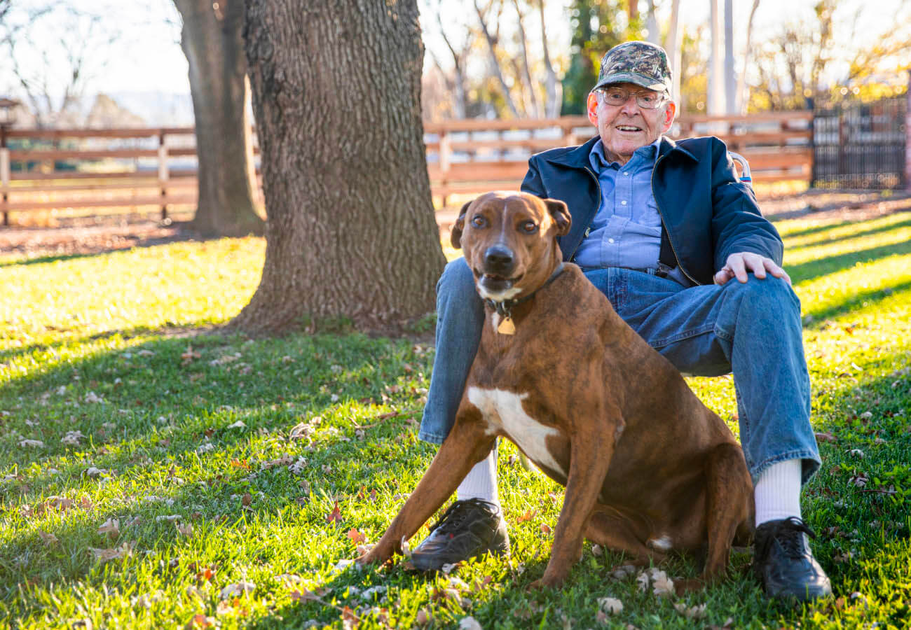 A man sitting in the yard with a dog