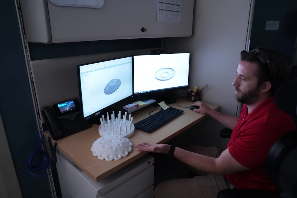 A person showing the 3d printed makeup brush holder by the 3d design on a computer