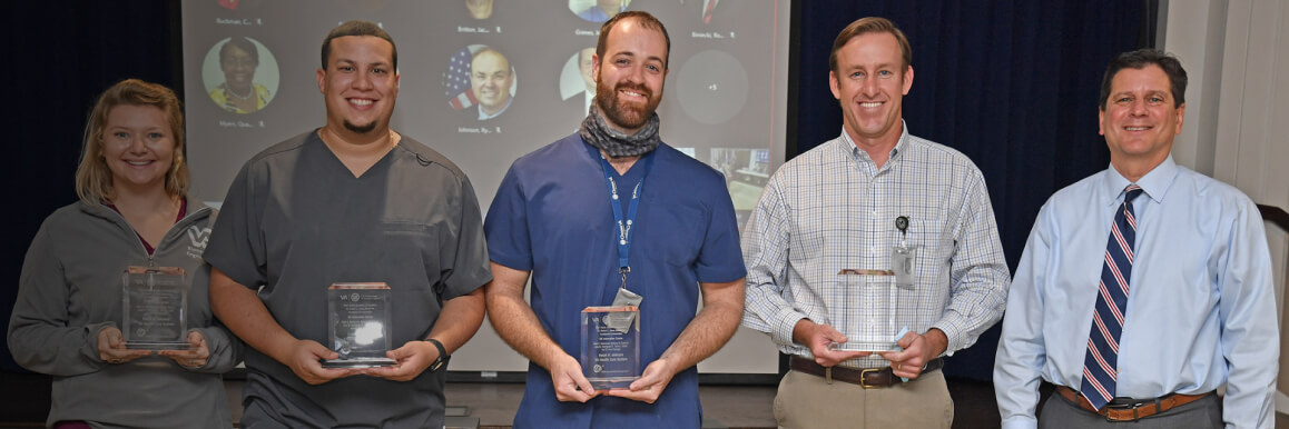 A group of 4 men and 1 woman holding awards